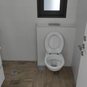 אסלה לבנה בחדר אמבטיה עם רצפת עץ