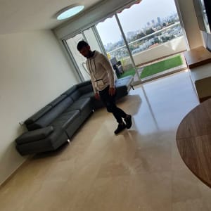 אדם עומד על רצפה נקייה בסלון מואר