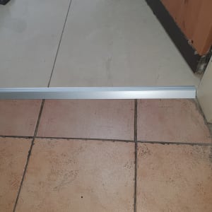 פס מתכת מותקן על רצפה בין אריחים