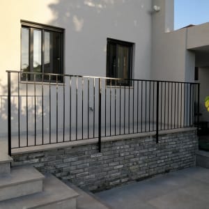 מעקה מתכת שחור על קיר לבנים אפור