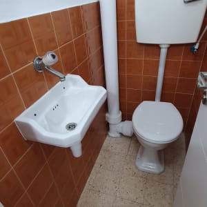 כיור ושירותים בחדר אמבטיה קטן עם אריחים חומים