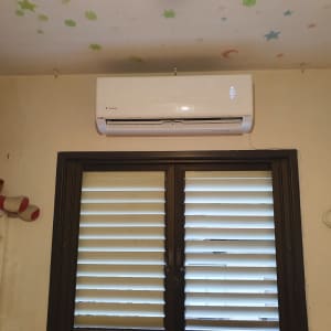 מזגן מותקן מעל חלון עם תריסים סגורים