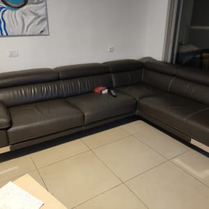 ספה פינתית חומה עם שלט וטישו על המושב