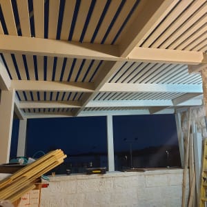 פרגולה מעץ עם קורות עץ וכלים על הקיר