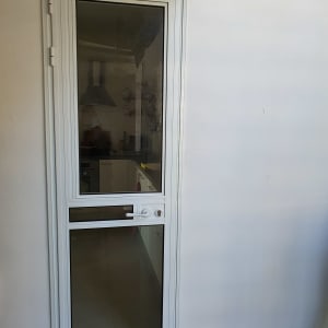 דלת אלומיניום עם זכוכית שקופה וקיר לבן