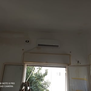 מזגן מותקן על קיר מעל חלון פתוח