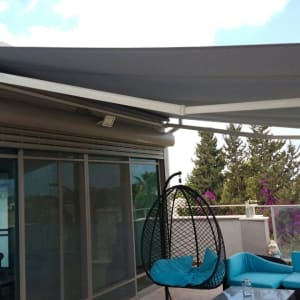 סוכך אפור נפתח מעל מרפסת עם ריהוט חוץ