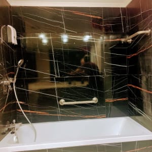 אמבטיה עם אריחים שחורים, מוט אחיזה וברז חדש