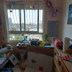 חדר מבולגן עם קופסאות קרטון, מגירות, שולחן וחלון