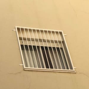 חלון עם סורגים לבנים על קיר חיצוני