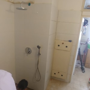 עובד מתקין אריחים בחדר אמבטיה עם כלים וחומרים