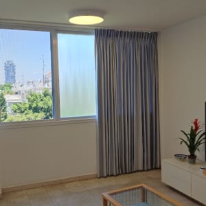 וילון אפור תלוי ליד חלון גדול בסלון