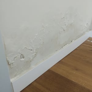 קיר עם רטיבות ונזקי מים ליד הרצפה