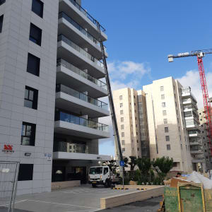 מנוף לבן ליד בניין מגורים גבוה