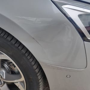 שריטות על פגוש רכב אפור ליד גלגל קדמי