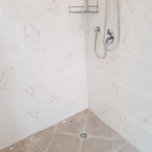 מקלחת עם אריחים חדשים ומדף מתכת