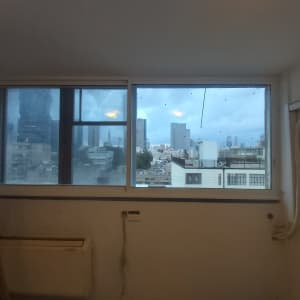 חלון אלומיניום עם נוף עירוני ברקע