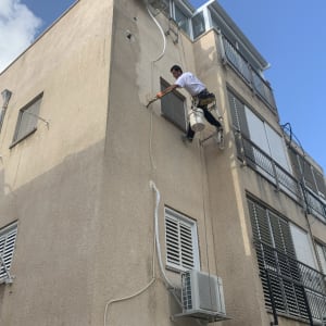 אדם צובע קיר חיצוני של בניין גבוה