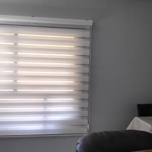 וילון זברה לבן על חלון קיר אפור