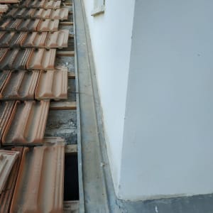 רעפים על גג ליד קיר לבן עם פח