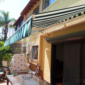 סוכך פסים ירוק ולבן מותקן על קיר חיצוני