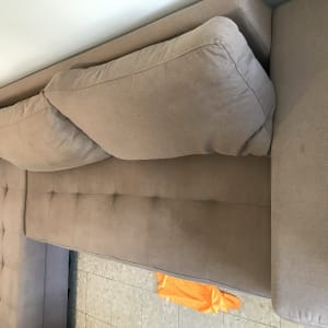 ספה חומה עם כריות ומטלית כתומה על הרצפה