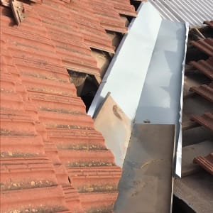 רעפים אדומים על גג עם תעלה מתכתית