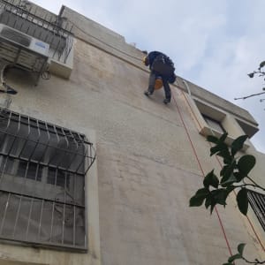 אדם על חבל מבצע איטום קיר חיצוני