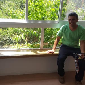 אדם מחזיק אקדח סיליקון ליד חלון עץ