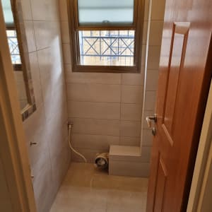 חדר אמבטיה בשיפוץ עם אריחים וצינור חשוף