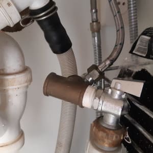 צינורות פלסטיק וברז מתכת מתחת לכיור