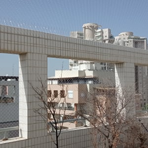 רשת יונים מותקנת על מרפסת עם דוקרנים על הקיר