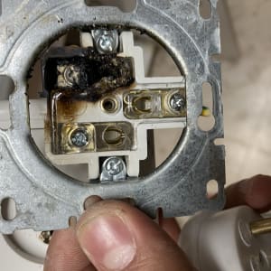 שקע חשמלי עם סימני שריפה וברגים חשופים