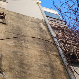 קיר בניין גבוה עם סדקים וצינור מתכת