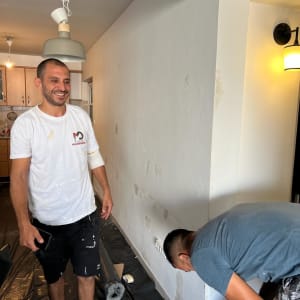 שני אנשים עובדים על צביעת קיר בחדר