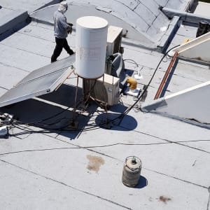 אדם עובד על איטום גג עם יריעות ביטומניות.