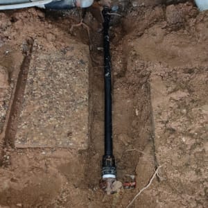 צינור שחור מונח בתעלה באדמה חשופה