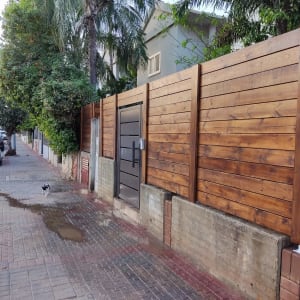גדר עץ חומה עם שער מתכת בצד הדרך
