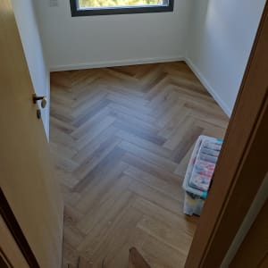 רצפת פרקט עץ בהתקנה בחדר קטן עם חלון