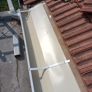 מרזב מתכת ליד רעפים שבורים על גג