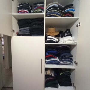 ארון בגדים מסודר עם מדפים מלאים בבגדים מקופלים