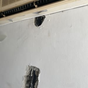 חורים בקיר עם צינורות חשופים מתחת למזגן