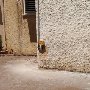 צינור חשמל על קיר חיצוני עם שלט אזהרה