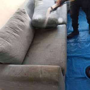 ניקוי ספה עם מכשיר קיטור על יריעת פלסטיק כחולה