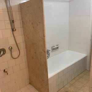 חדר אמבטיה עם אריחים לבנים, מקלחון ואמבטיה