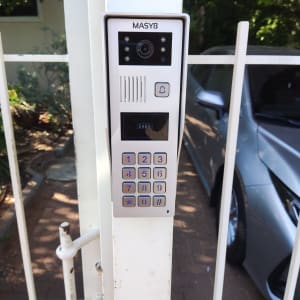 אינטרקום עם מצלמה ומקשים על שער לבן