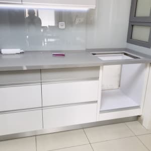 מטבח מודרני עם ארונות לבנים ומשטח עבודה אפור