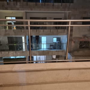 מעקה זכוכית עם מסגרת מתכת במרפסת בניין