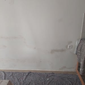 קיר עם תיקוני טיח ויריעת מגן על הרצפה