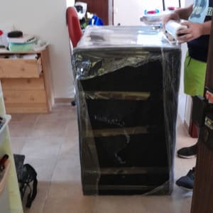 אדם עוטף רהיט בניילון לקראת מעבר דירה